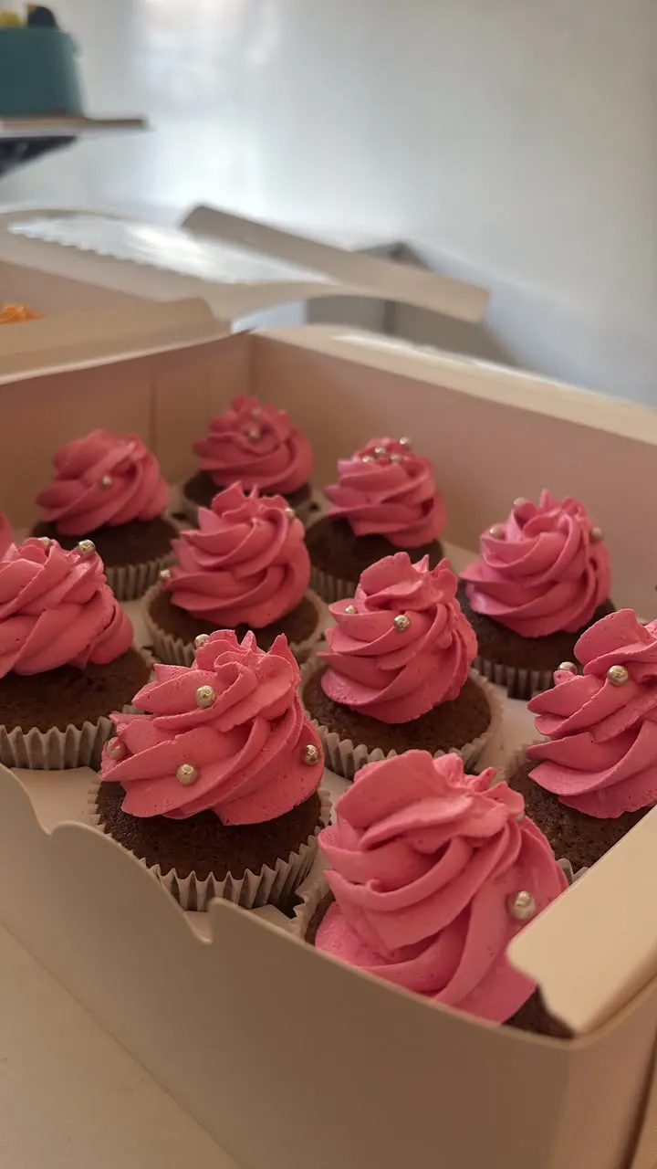 Box of cupcakes with pink and raspberry frosting