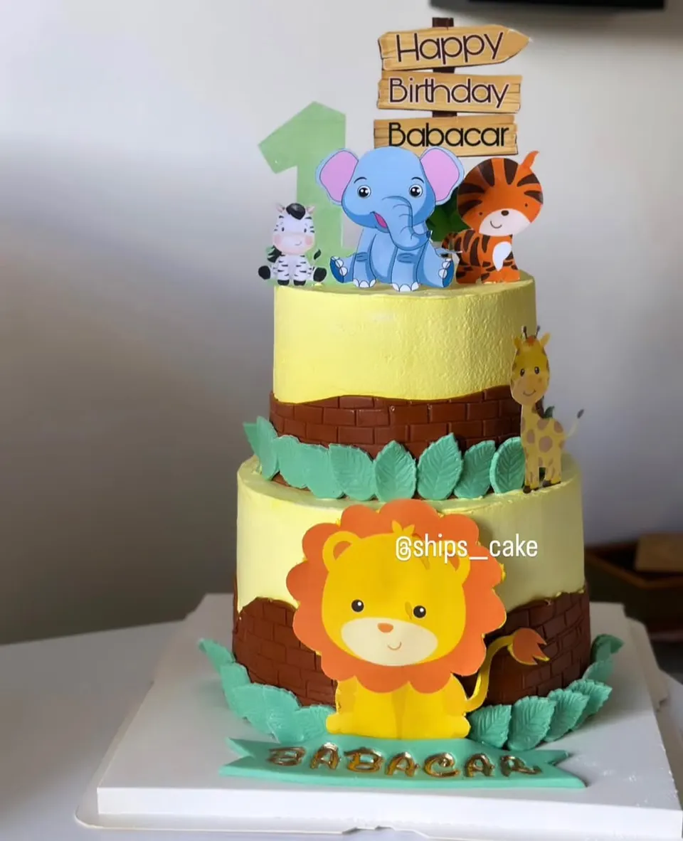 Three-tier jungle-themed cake with a fondant lion and elephant