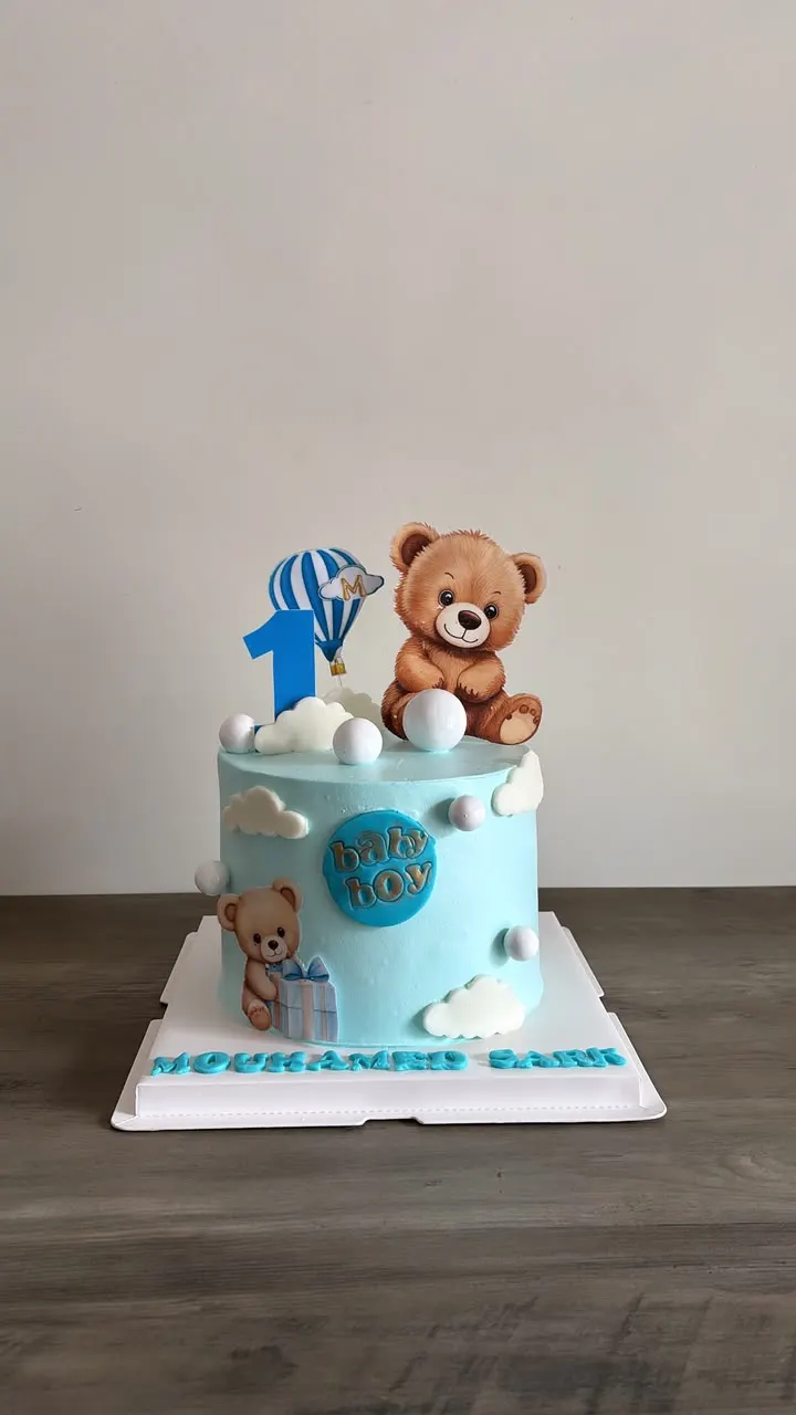 Sky-blue first birthday cake with a fondant teddy bear and the number 1