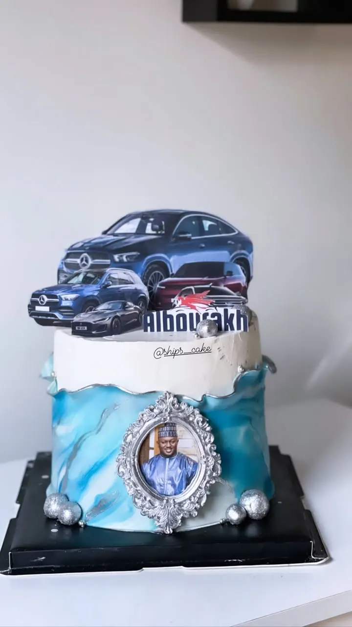 Blue and white cake decorated with cars and a photo medallion