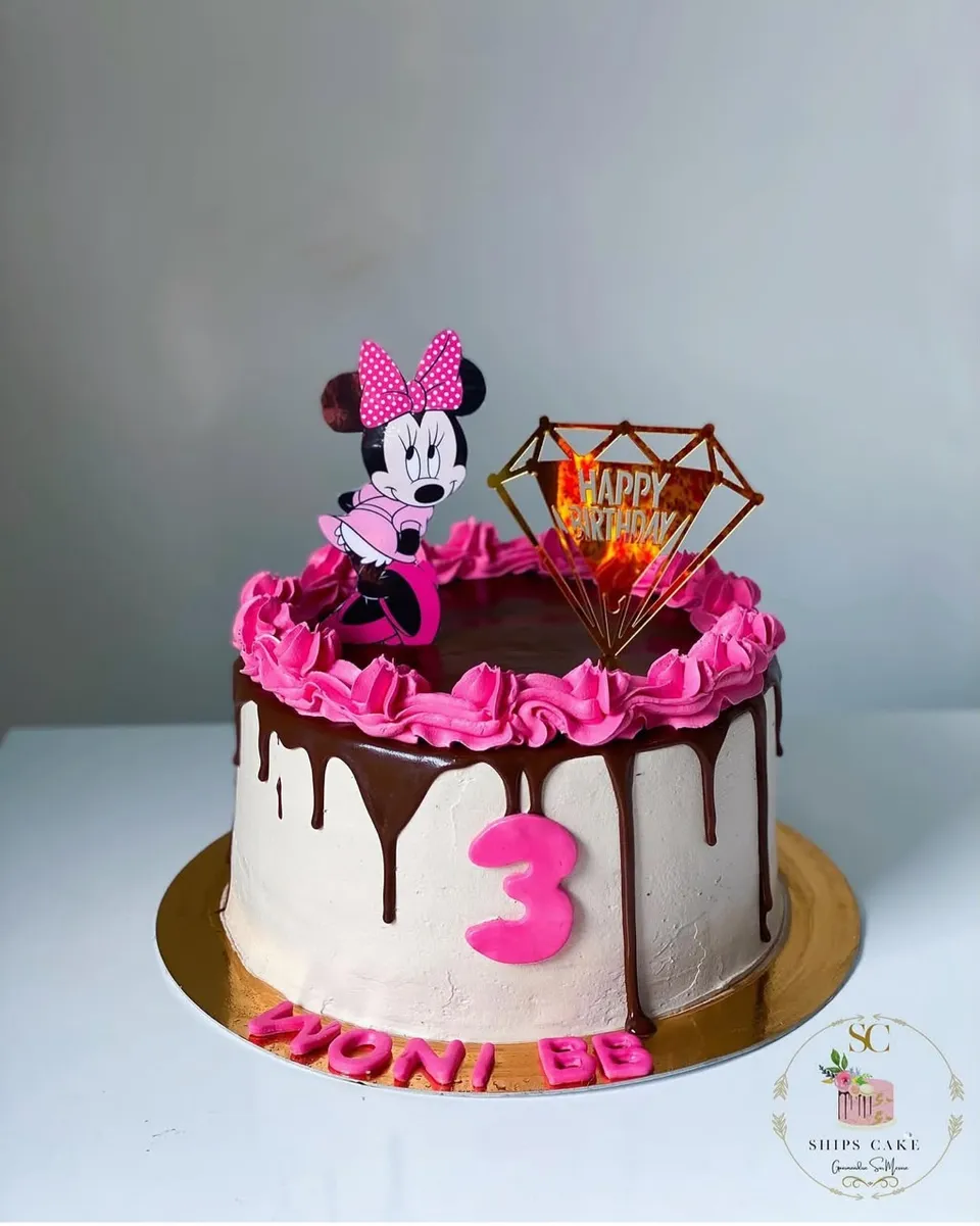 Chocolate drip cake with pink rosettes and a Minnie decoration