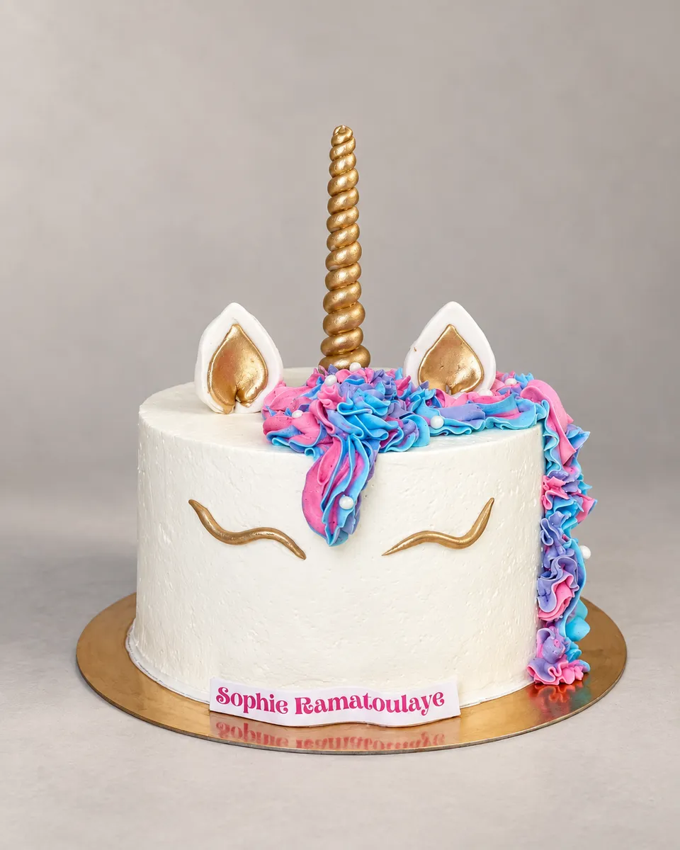 White unicorn cake with a gold horn and ears and a pink, blue and mauve mane