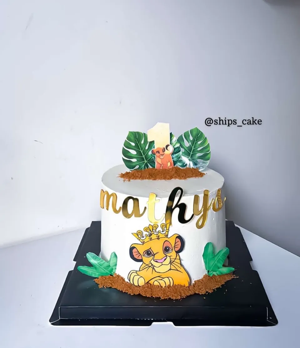 White Lion King cake with a lion cub and tropical leaves