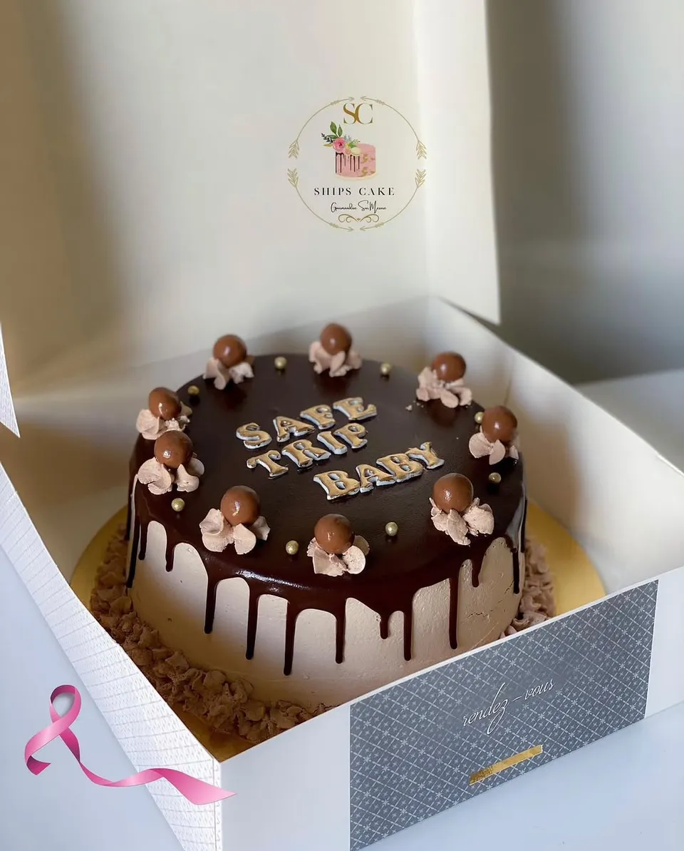 Chocolate cake under a ganache glaze, with chocolate balls, cream rosettes and gold pearls
