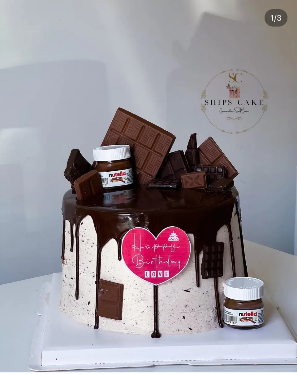Chocolate drip cake topped with chocolate bars and a jar of hazelnut spread