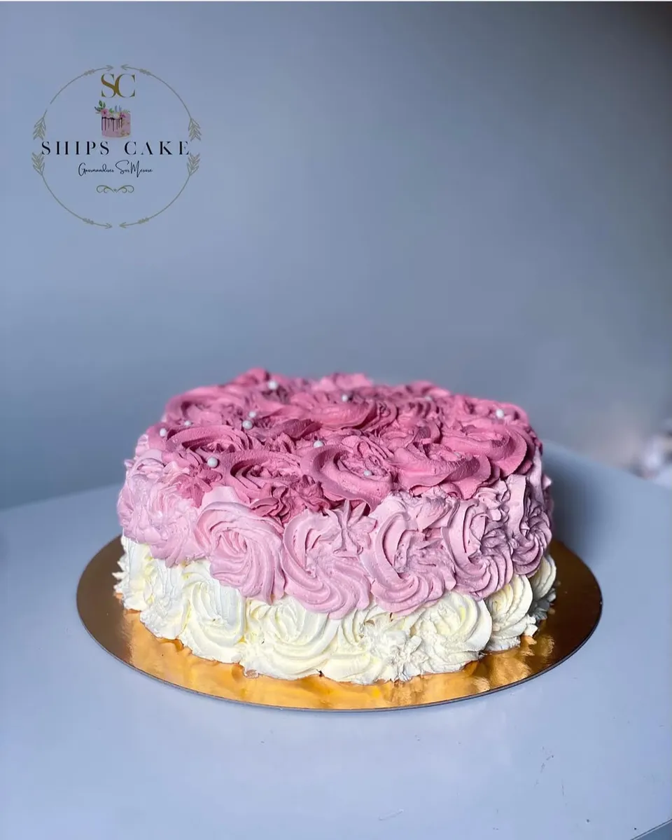 Cake covered in cream rosettes, shading from deep pink down to white
